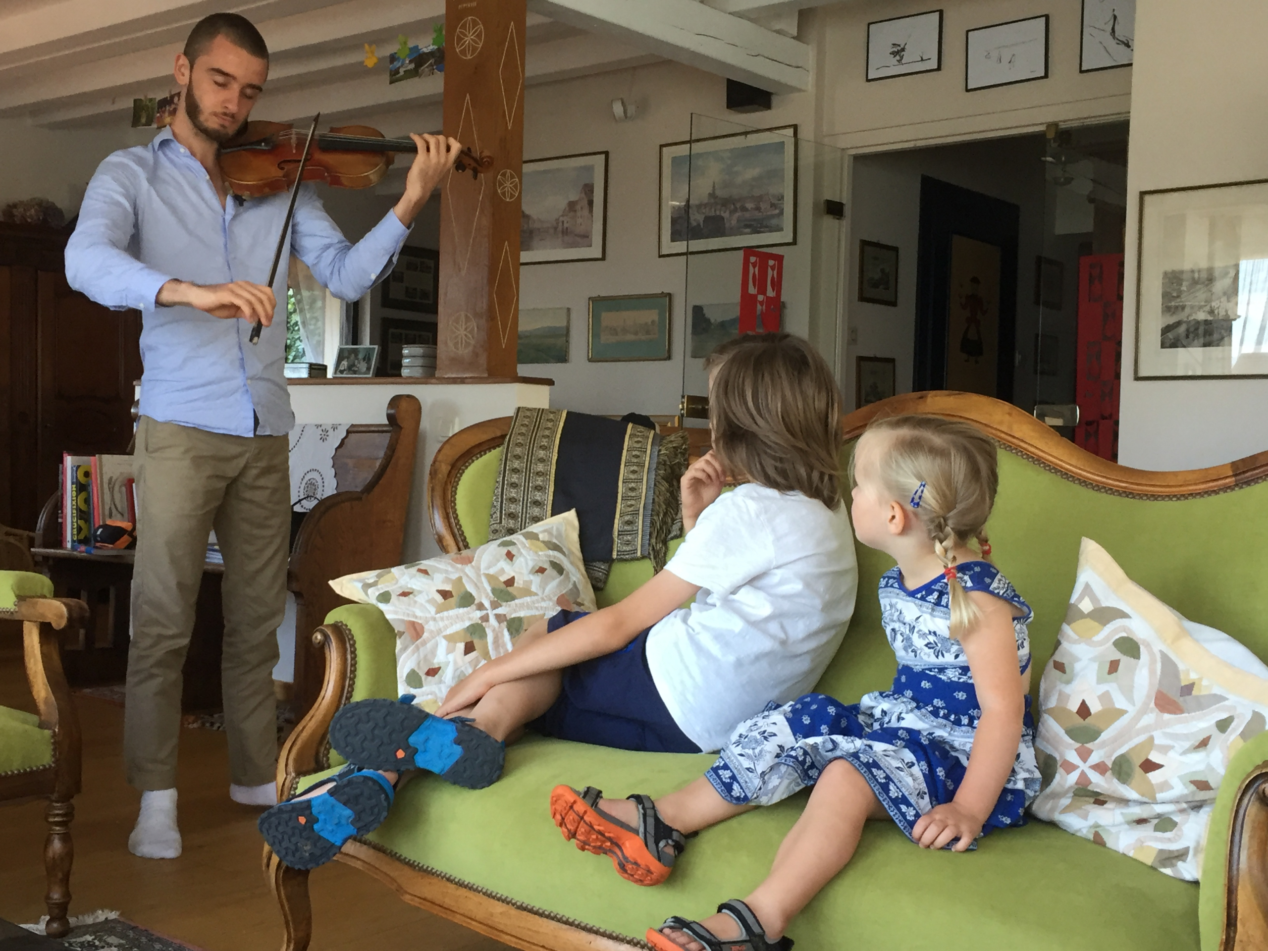 Deux des petits-enfants de Marie-Suzanne Weick-Voelckel, fascinés, écoutent Elie jouer le violon de leur arrière-grand-père